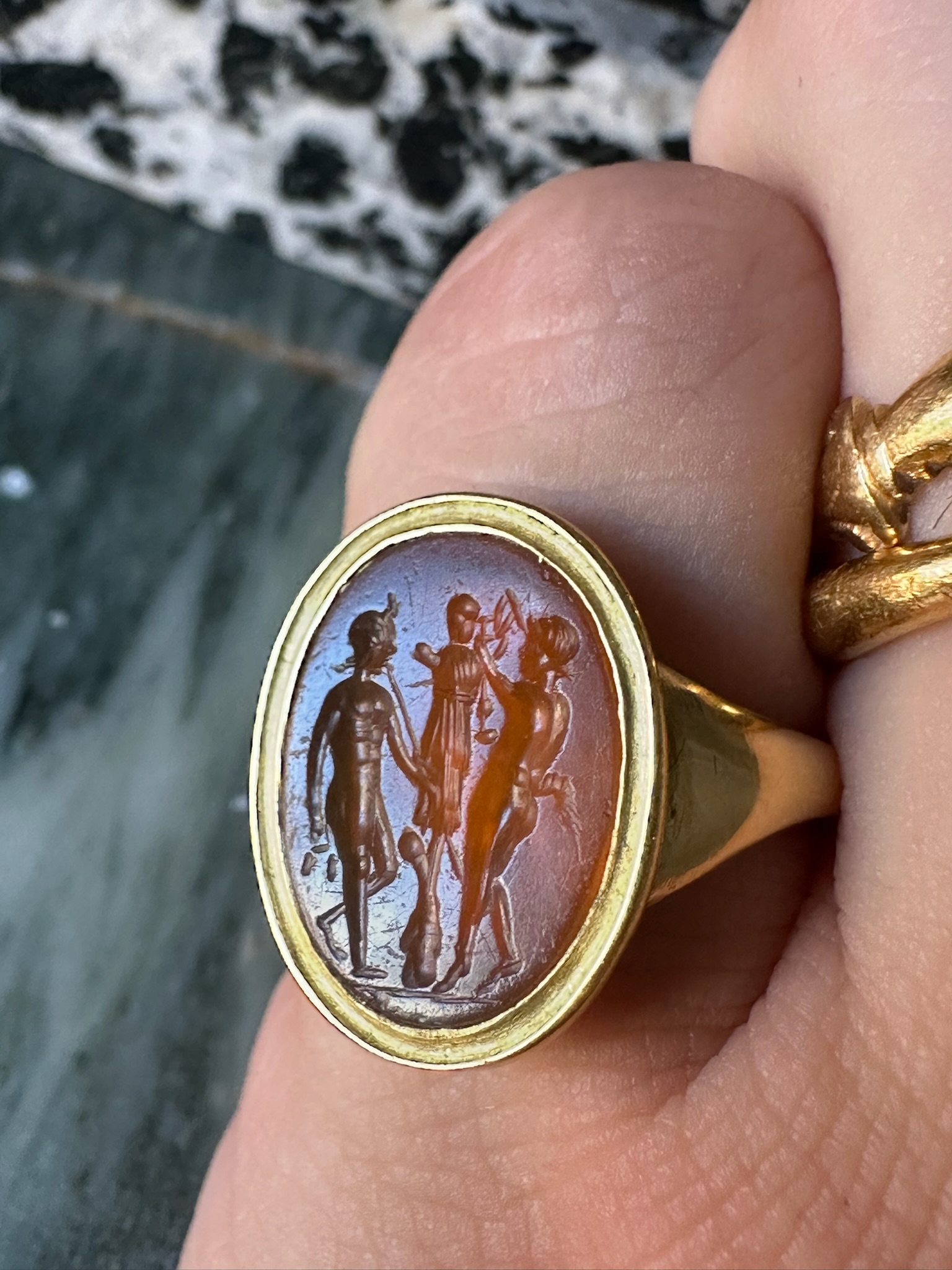 A gold ring set with a Roman Carnelian intaglio. Two Satyres crowning a trophy