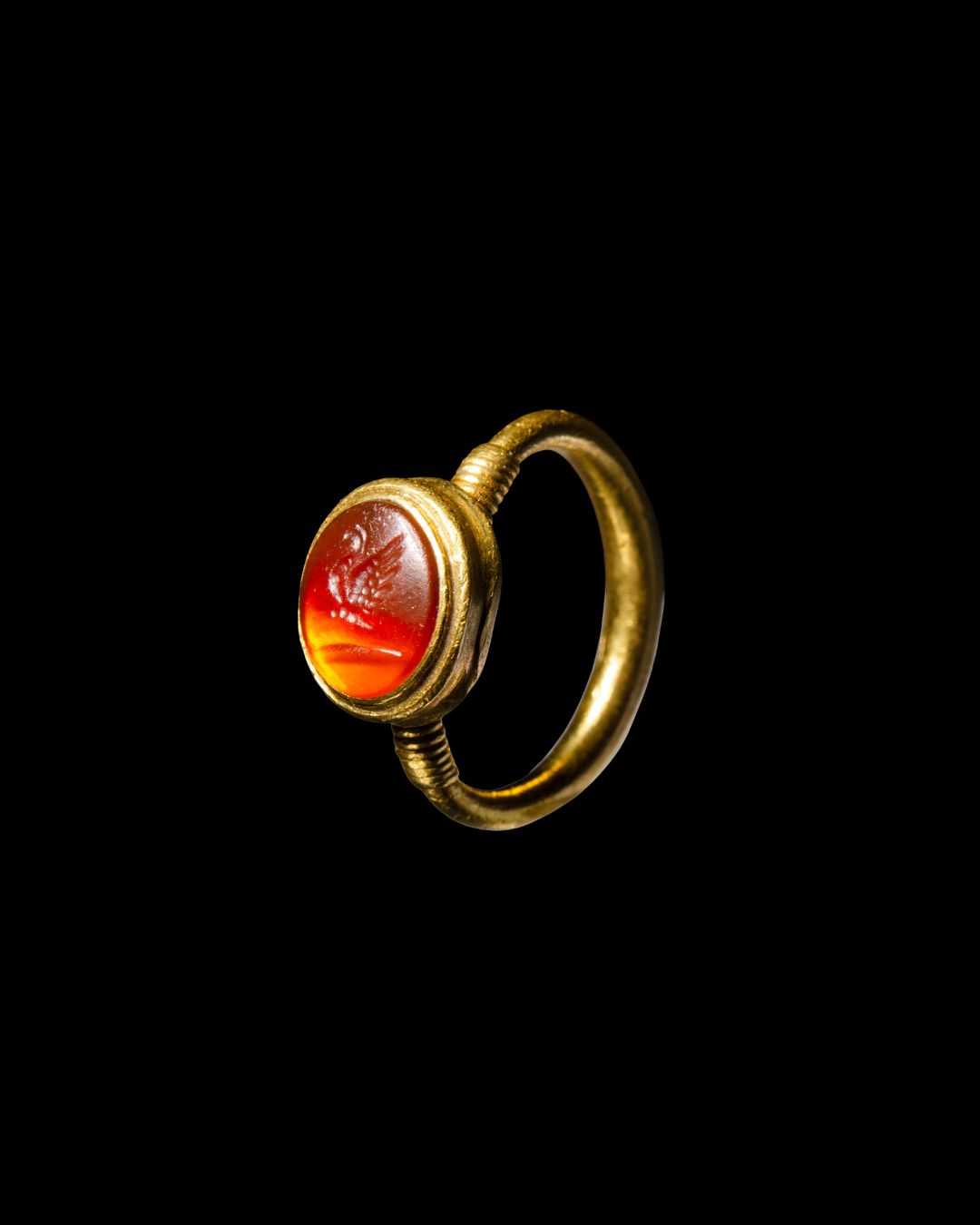 A High-carat gold ring set with a Roman carnelian intaglio of a butterfly on a palm branch