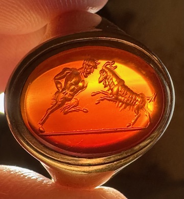 A 18k signet ring set with a Grand Tour carnelian intaglio. Pan fighting a goat. 