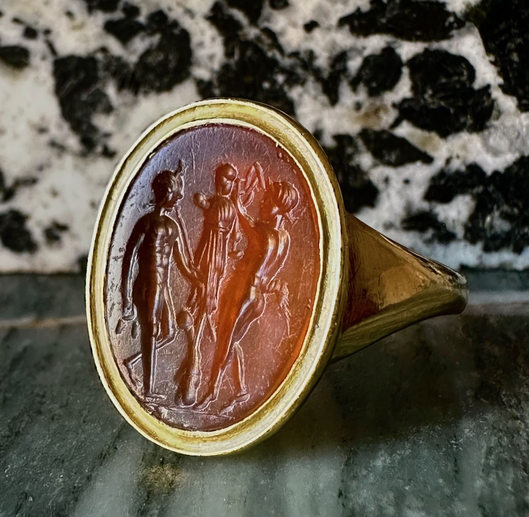 A gold ring set with a Roman Carnelian intaglio. Two Satyres crowning a trophy