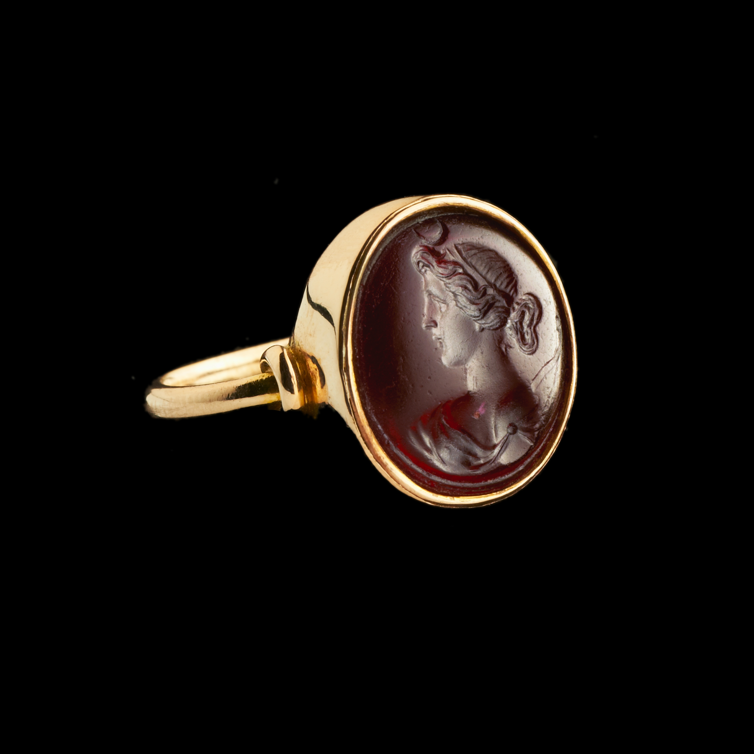 A gold ring set with a 19th century red glass intaglio. Bust of Diana.