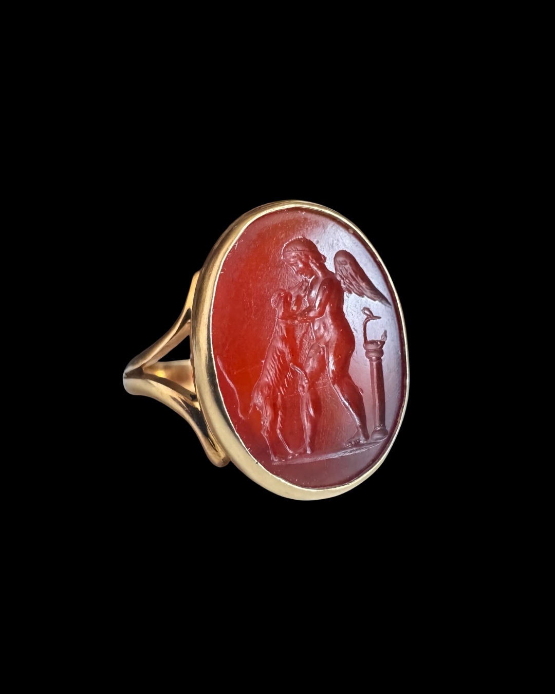 A Neoclassical gold ring set with a carnelian intaglio. Eros with a dog.