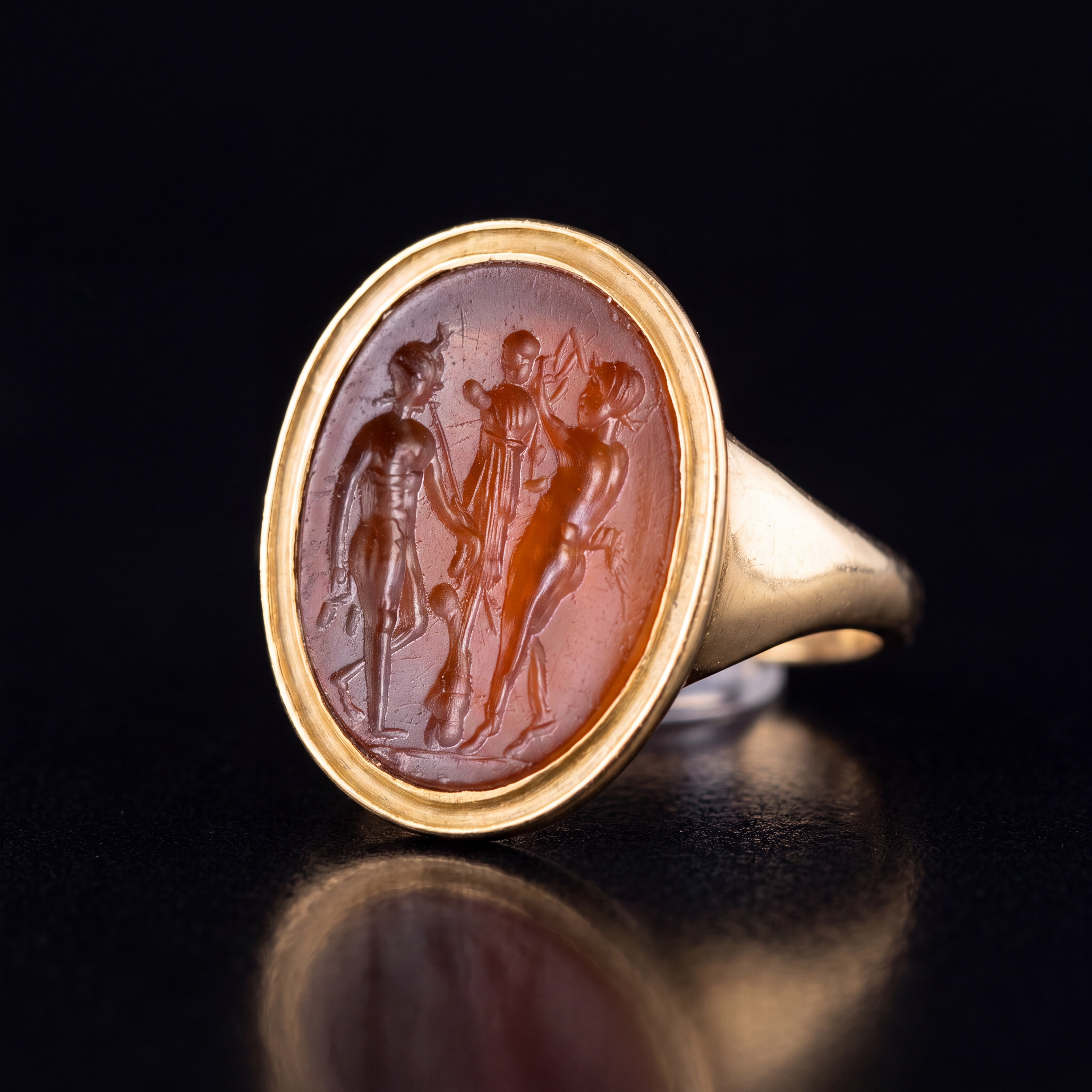 A gold ring set with a Roman Carnelian intaglio. Two Satyres crowning a trophy