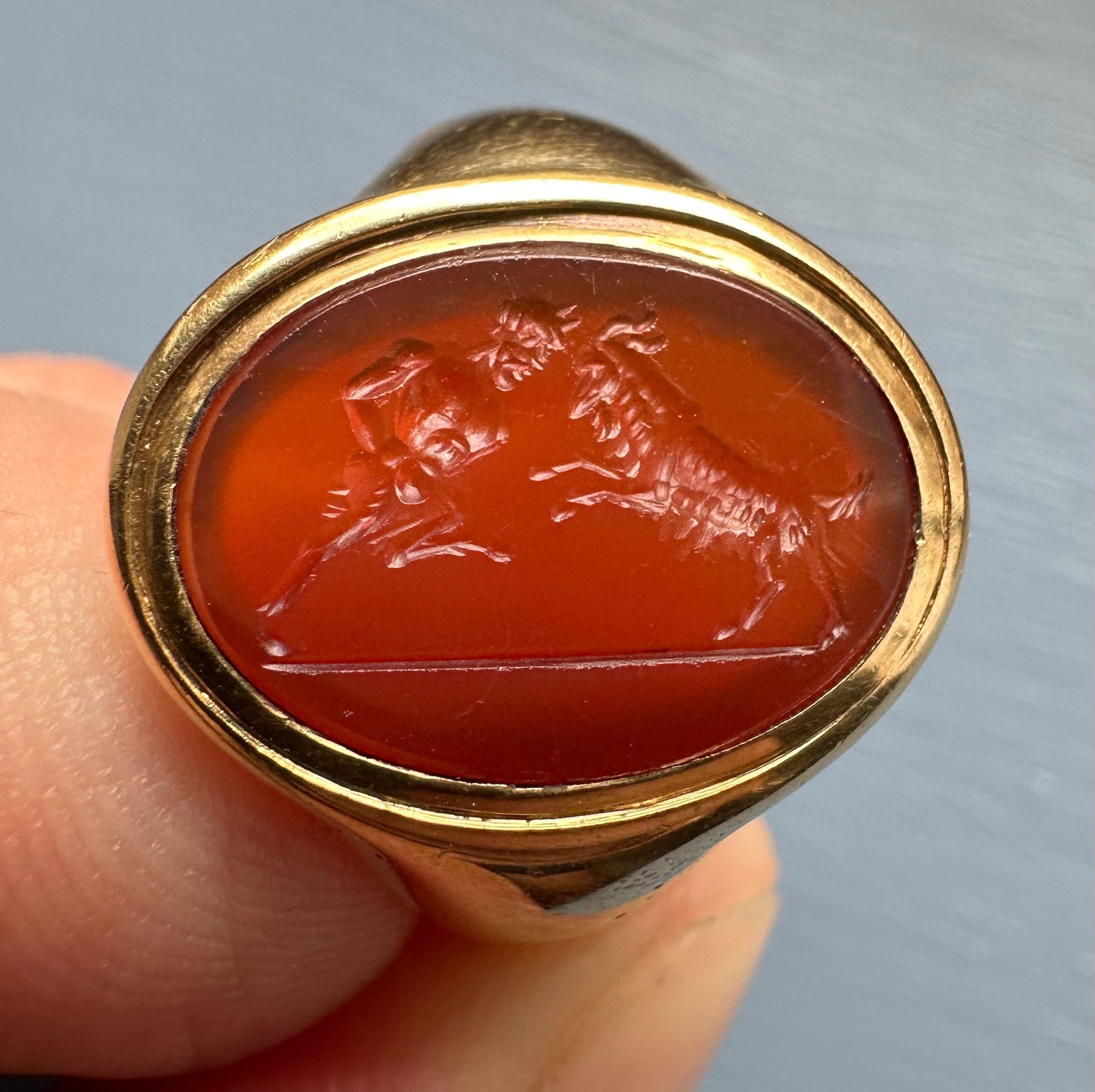 A 18k signet ring set with a Grand Tour carnelian intaglio. Pan fighting a goat. 
