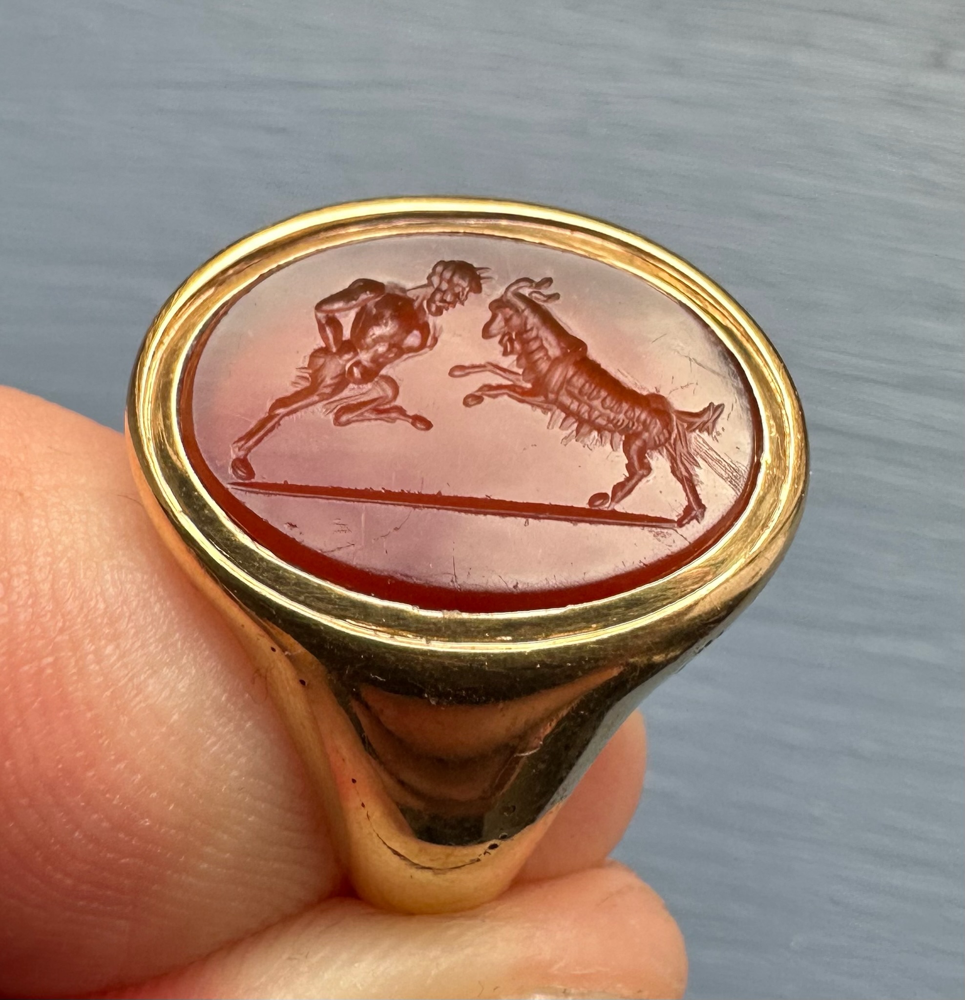 A 18k signet ring set with a Grand Tour carnelian intaglio. Pan fighting a goat. 