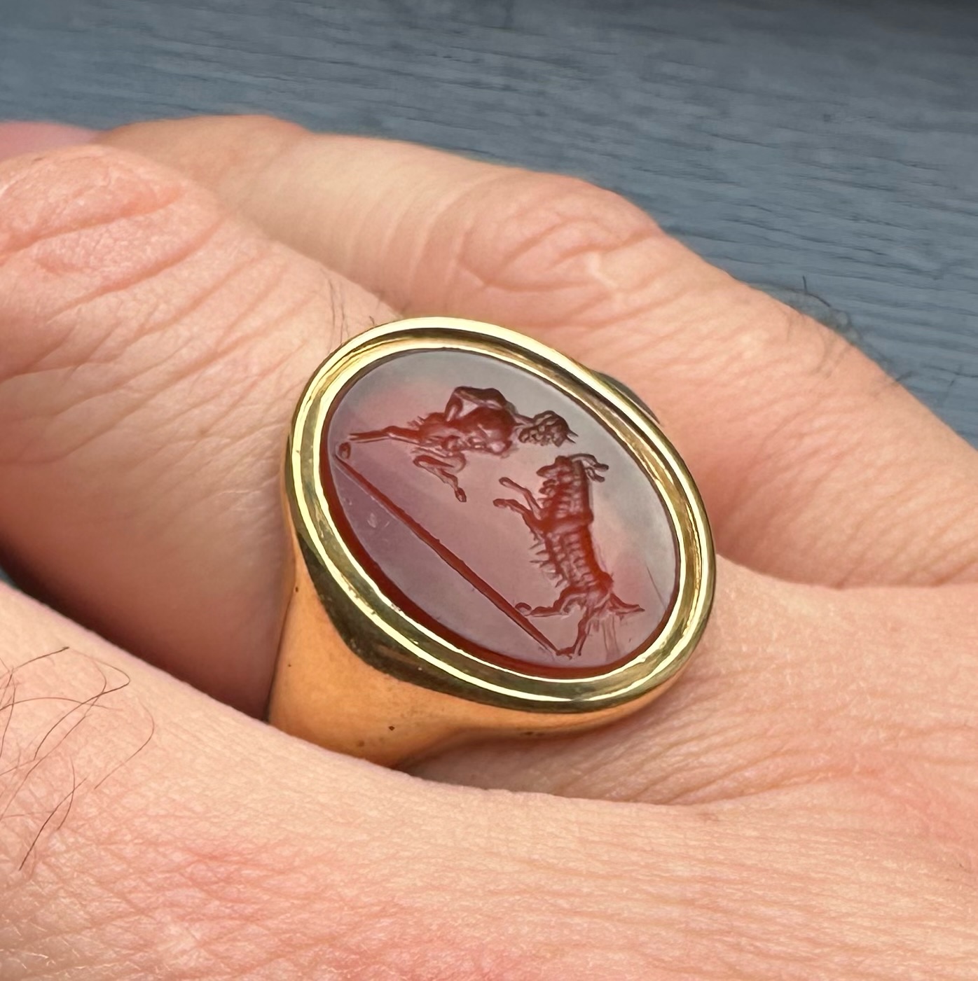 A 18k signet ring set with a Grand Tour carnelian intaglio. Pan fighting a goat. 