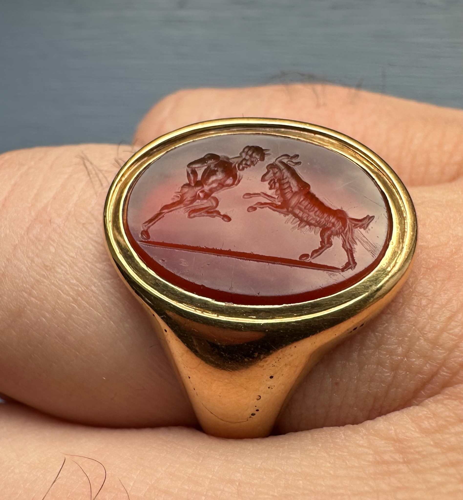 A 18k signet ring set with a Grand Tour carnelian intaglio. Pan fighting a goat. 