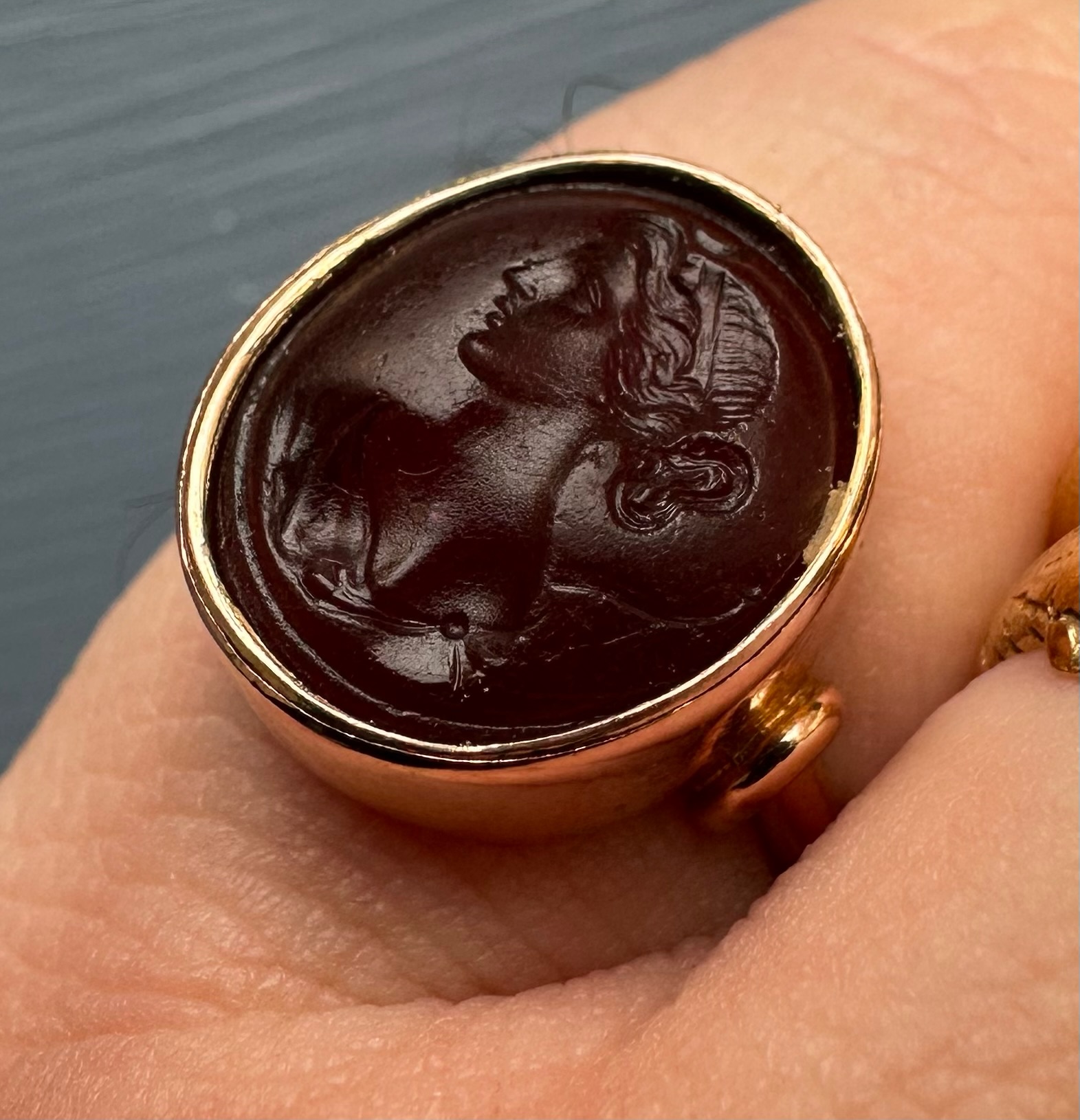 A gold ring set with a 19th century red glass intaglio. Bust of Diana.