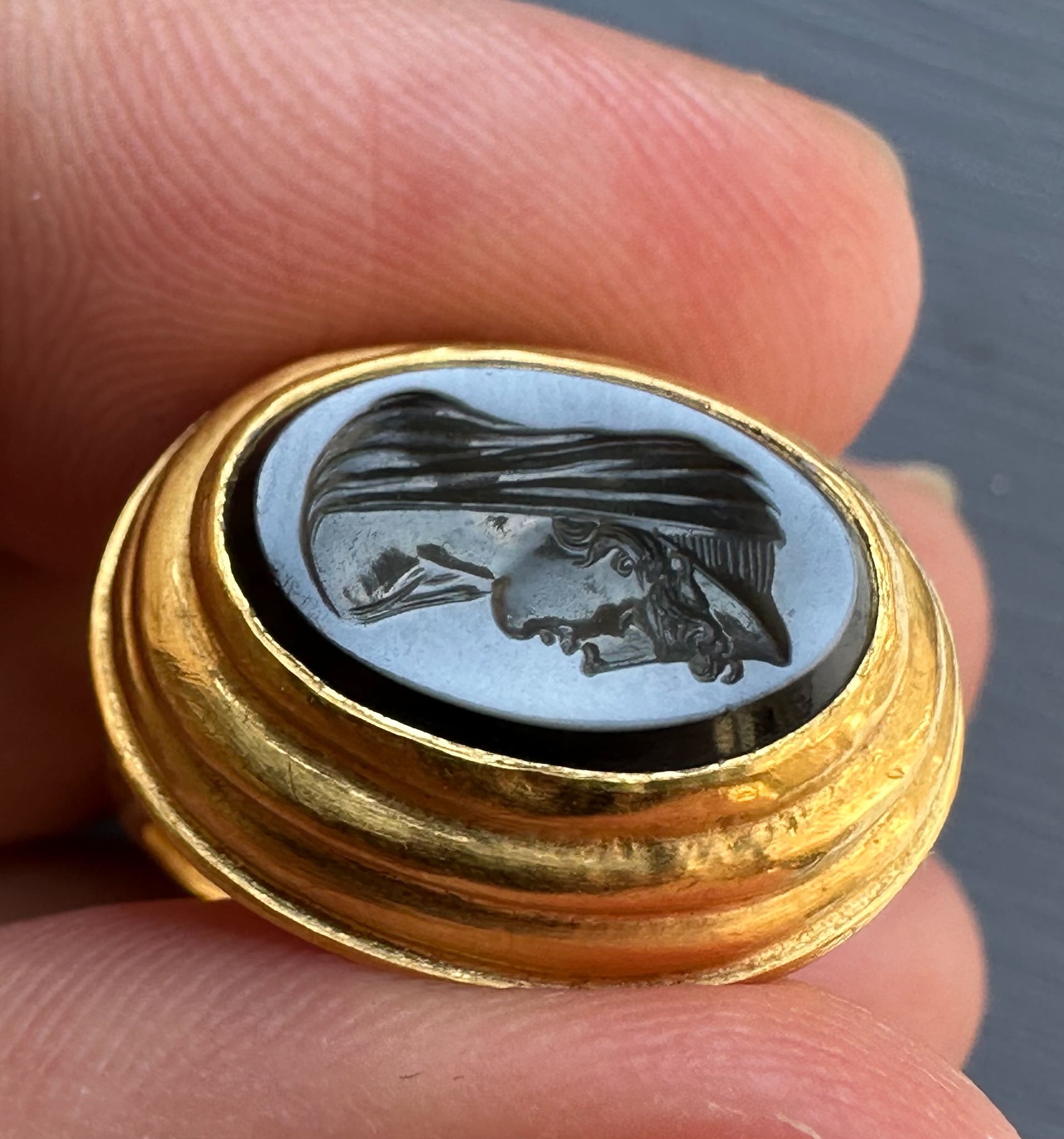 A 19th c. massive gold ring set with a nicolo intaglio. Veiled Juno. 