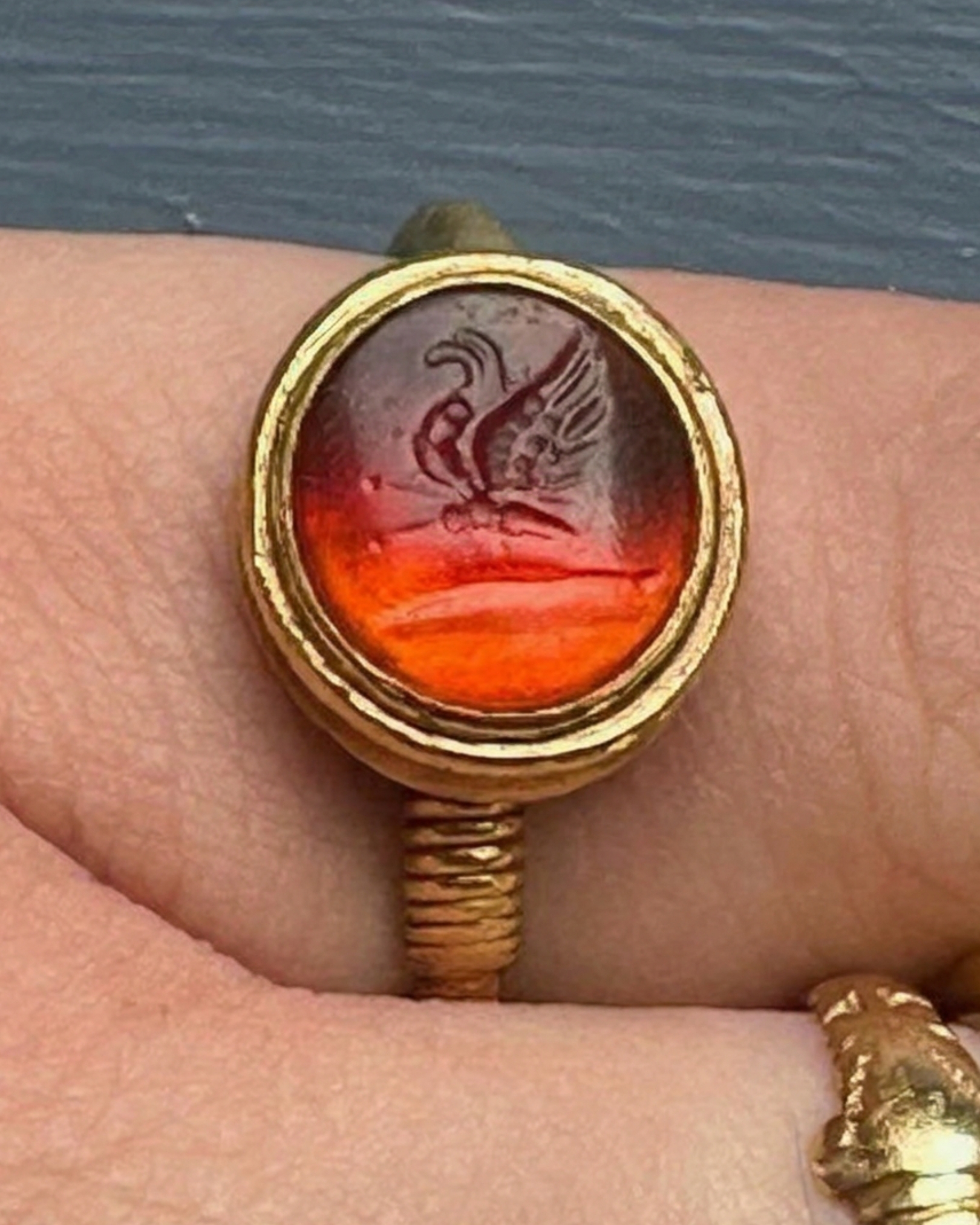 A High-carat gold ring set with a Roman carnelian intaglio of a butterfly on a palm branch
