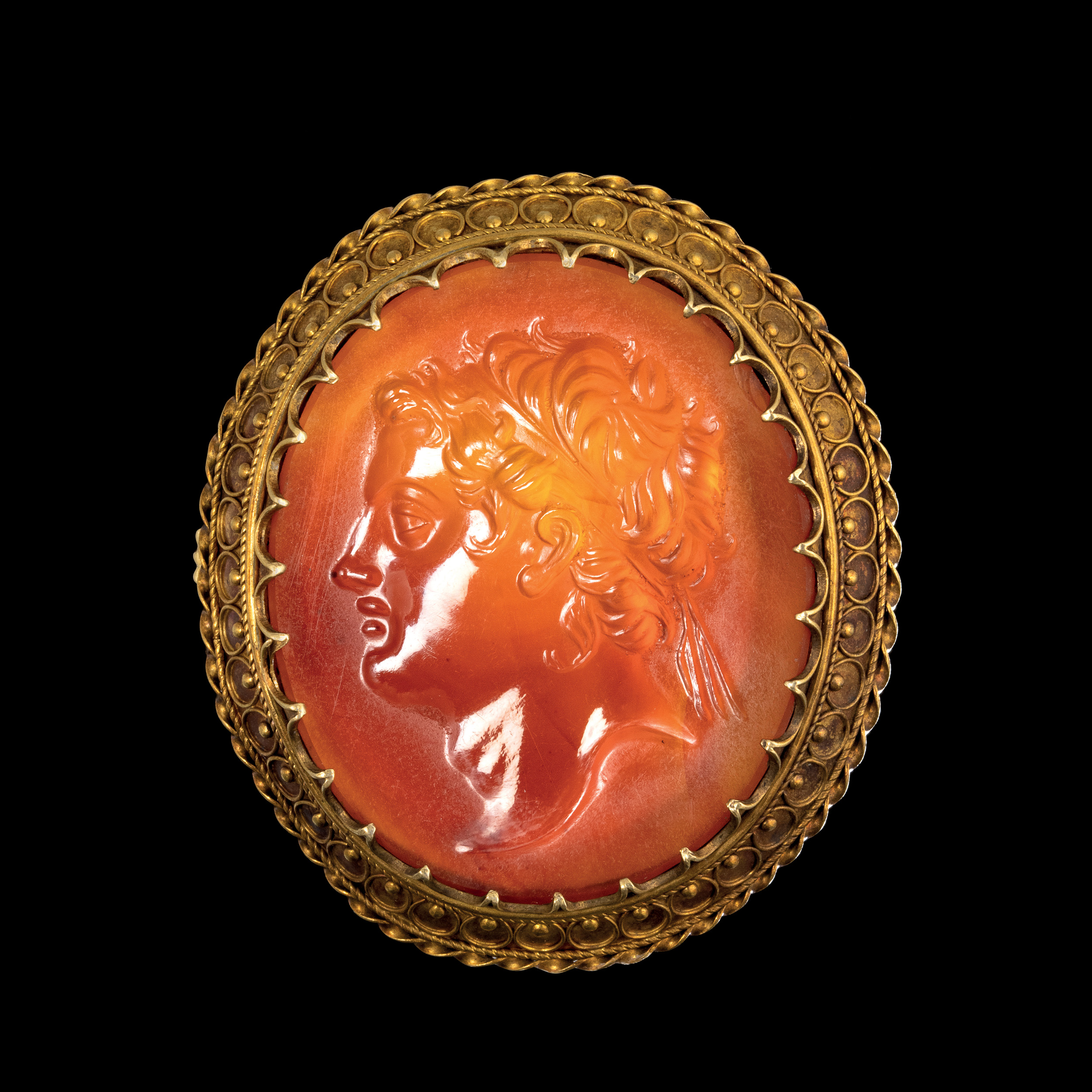 A 19th century gold brooch set with a large carnelian intaglio. Portrait of an Hellenistic ruler.